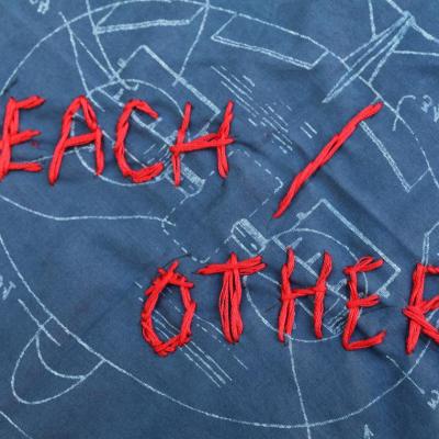 The words "Each Other" embroidered on a bandana