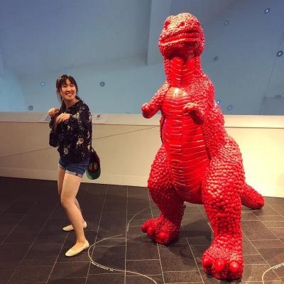 Girl posing in front of red dinosaur sculpture