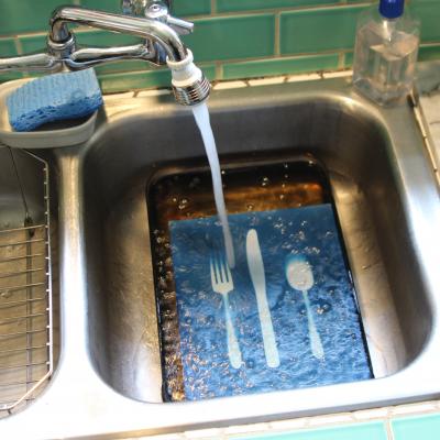 A cyanotype print getting rinsed with water in the kitchen sink