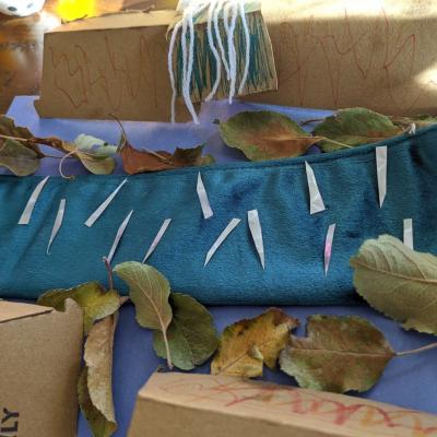 A child's collage made from fabric, paper, cardboard, leaves, and yarn. It resembles a waterfall scene.