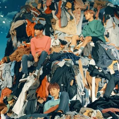 Members of BTS sitting on a mountain of clothes.