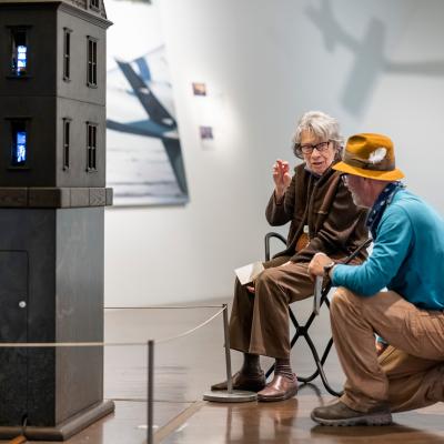 Two older visitors talking and examining a sculpture