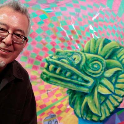 Photograph of artist Carlos Frésquez with his artwork in the background.