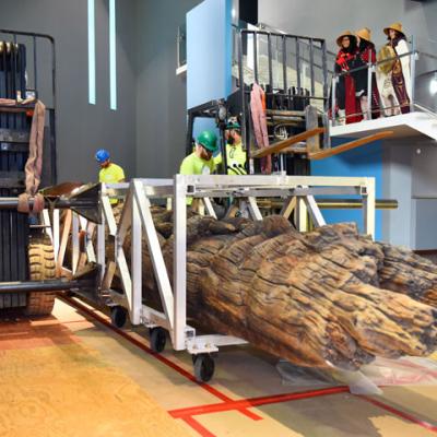 construction workers with one of the Haida poles with members of the Wallace family looking on from the stairs above