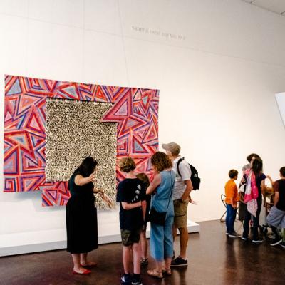 visitors in front of a large wall hanging