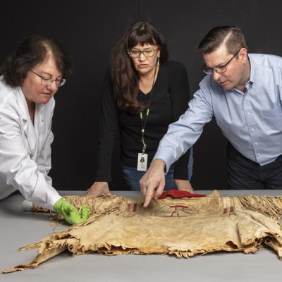 DAM curator John Lukavic examining an upper Missouri shirt.
