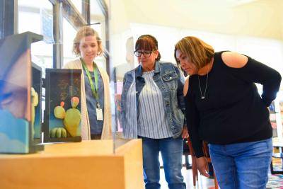 Teachers and staff at the Denver Art Museum looking at Outside In: Contemporary Landscape Art exhibition setup in community center