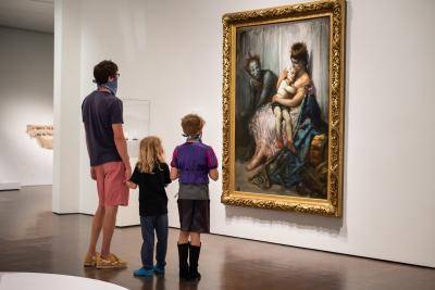 Father looking at a painting with his son and daughter