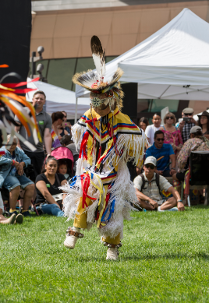 Dancing child dressed in traditional Native American attire at Denver Art Museum's Powwow