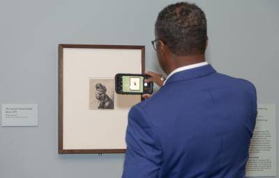 Gentleman taking a photo of an artwork with his cell phone