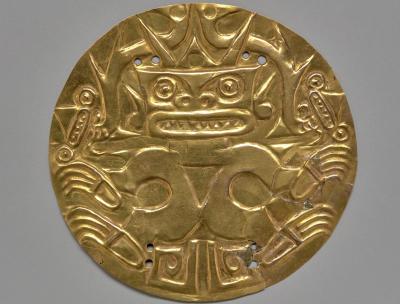 gold round breast plate engraved with a figure on it