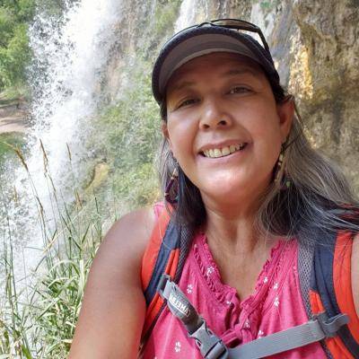 Felicia Alvarez wearing hiking clothes taking a selfie in front of a waterfall
