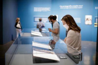 Masked visitors looking down at art in glass cases