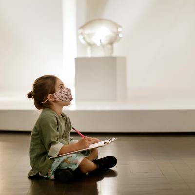 a girl sits on the floor and draws in a gallery
