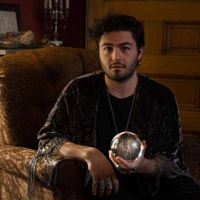 Cooper Kaminsky in a chair holding a mirror ball in his left hand