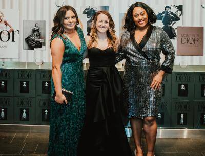 Three women in formal dresses posing for the camera at an event to celebrate the Dior exhibition