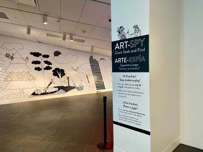 Instruction sign and mural for the Art Spy: Giant Seek and Find game in the galleries