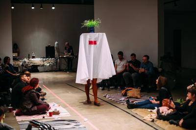 Woman walking own a runway dressed as a table with a plant on top of it
