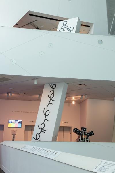 black and white drawings of figures climbing a column in the museum's atrium