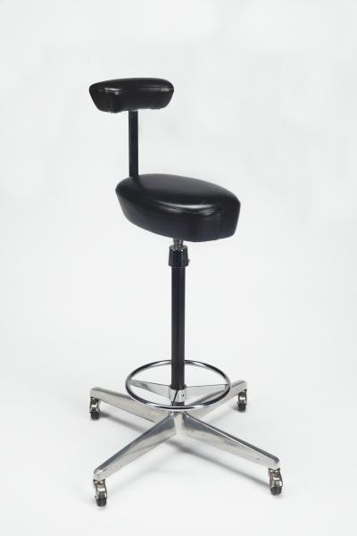 Tall task chair on metal casters. The seat is quite thin, and the back is shaped like an armrest, allowing it to serve as place to lean on.