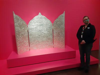 Rebecca Rowley next to a silver-colored sculpture in one of the art galleries