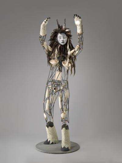 Large-scale sculpture of a human figure with its hands extended over its head.