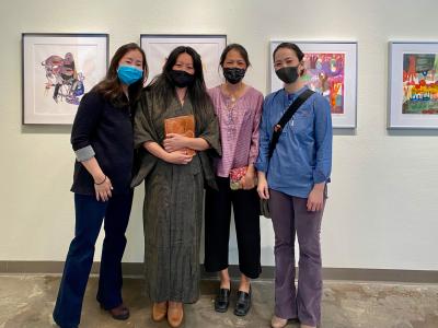 Jane Burke and three other women in front of paintings in the Colorado Asians art exhibition