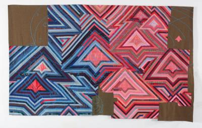 Large textile comprised of triangular patterns on a brown background. The pattern is mostly blue on the left, and mostly red on the right. A light blue thread is embroidered on the top to mimic the Star Trek Enterprise spaceship.