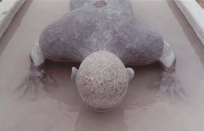 Sculpture of a naked man lying face down on a block of ice
