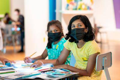 Two young masked girls doing arts and crafts