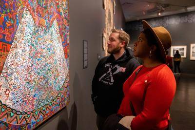 Man and woman examining colorful painting of Malinche