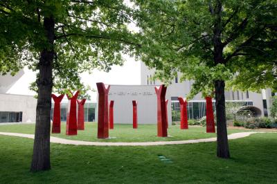 Circle of red sculptures admist a group of large green trees