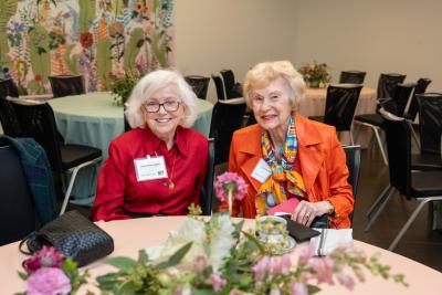 two women sit at a table at an event
