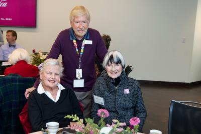 two women and a man at a table smiling at the camera