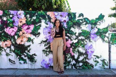 Ashley Joon standing in front of one of her outdoor murals of flowers