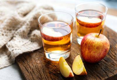two glasses with apple cocktail and apple slices and an apple on a table