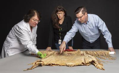 DAM curator John Lukavic examining an upper Missouri shirt.