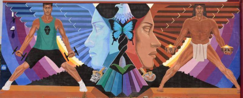 Mural of a man in athletic wear on the left and in a loincloth on the right, separated by a woman's face in the center