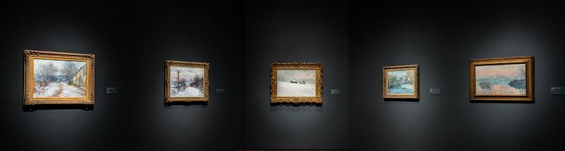 A series of Monet paintings hang on a dark grey gallery wall.