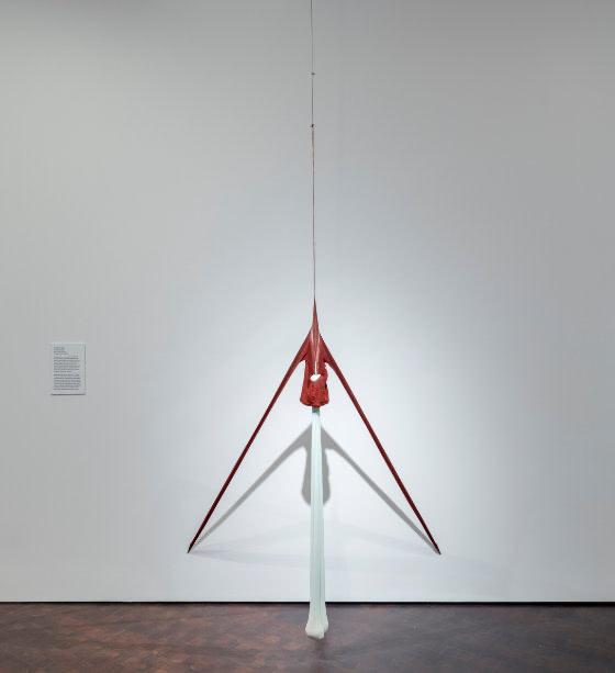 Tall triangular sculpture of light and dark nylon pantyhose suspended from the ceiling and stretched to the floor.