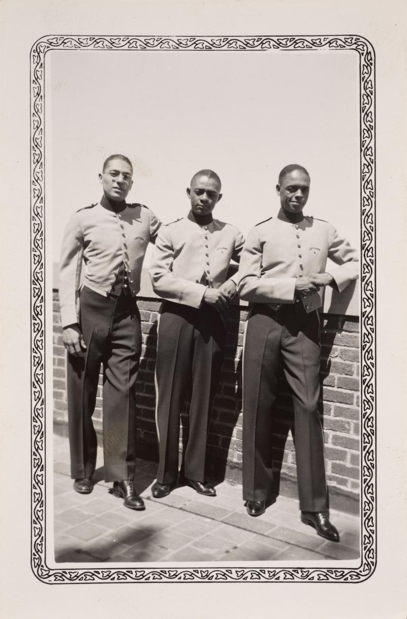 three men in bellhop uniforms on the roof