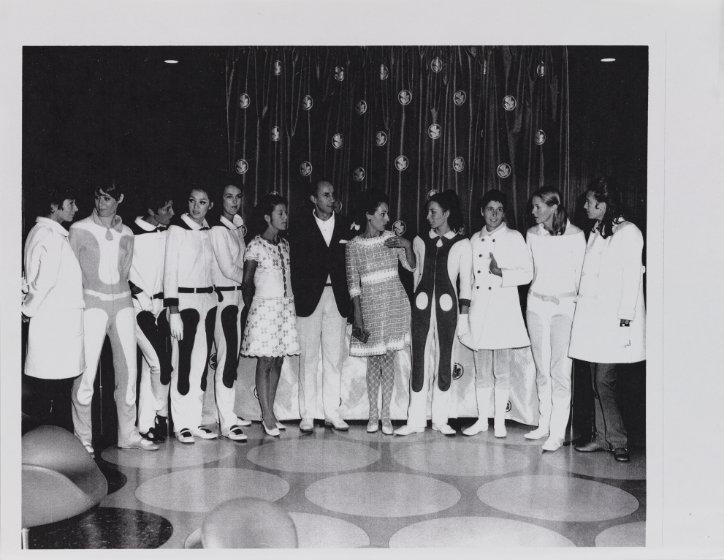 Fotografía en blanco y negro de doce personas de pie, lado a lado, sobre un escenario.