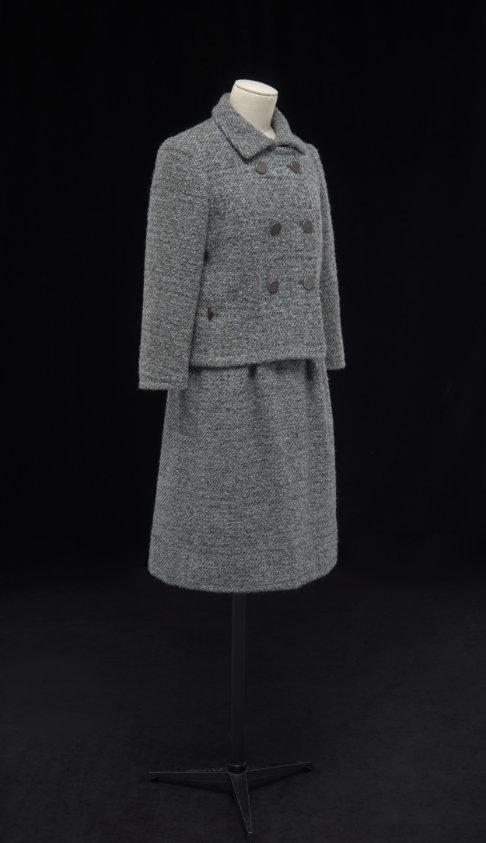 Gray suit with a collared, double-breasted jacket and a knee length skirt.