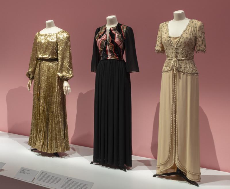Photograph of part of the exhibition that features six of Véronique’s dresses on mannequins with pink walls in the background.