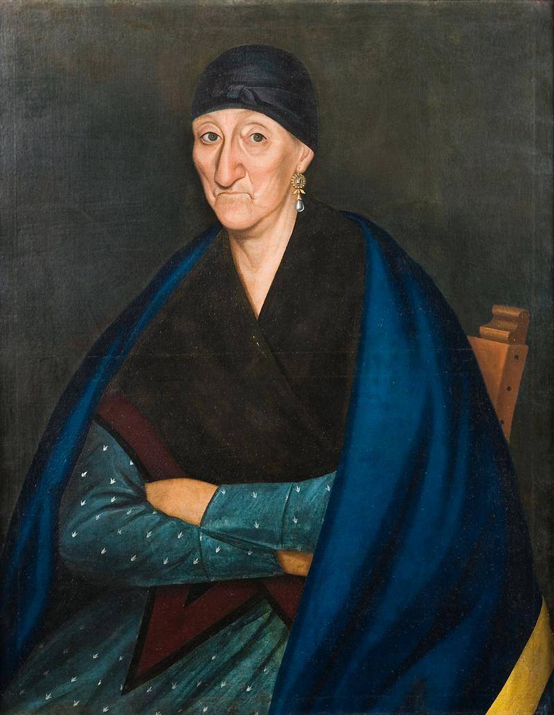 Portrait of an older woman in dark fabrics and large earrings.