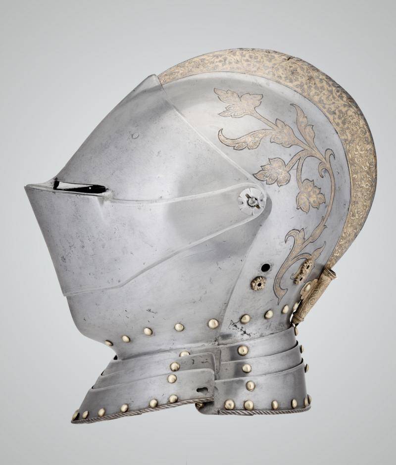 Profile view of a steel and brass tournament helmet that covers entire face and head