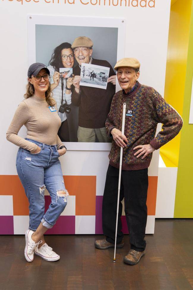 A grandfather and granddaughter pose next to their photo of each other in the exhibition