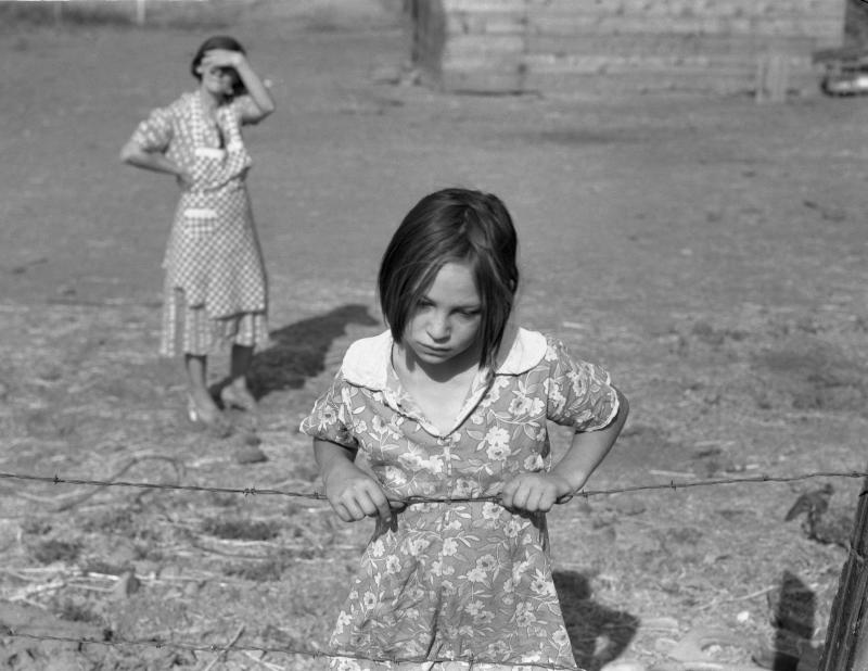 Black and white photograph of a young girl with her mother watching in the background