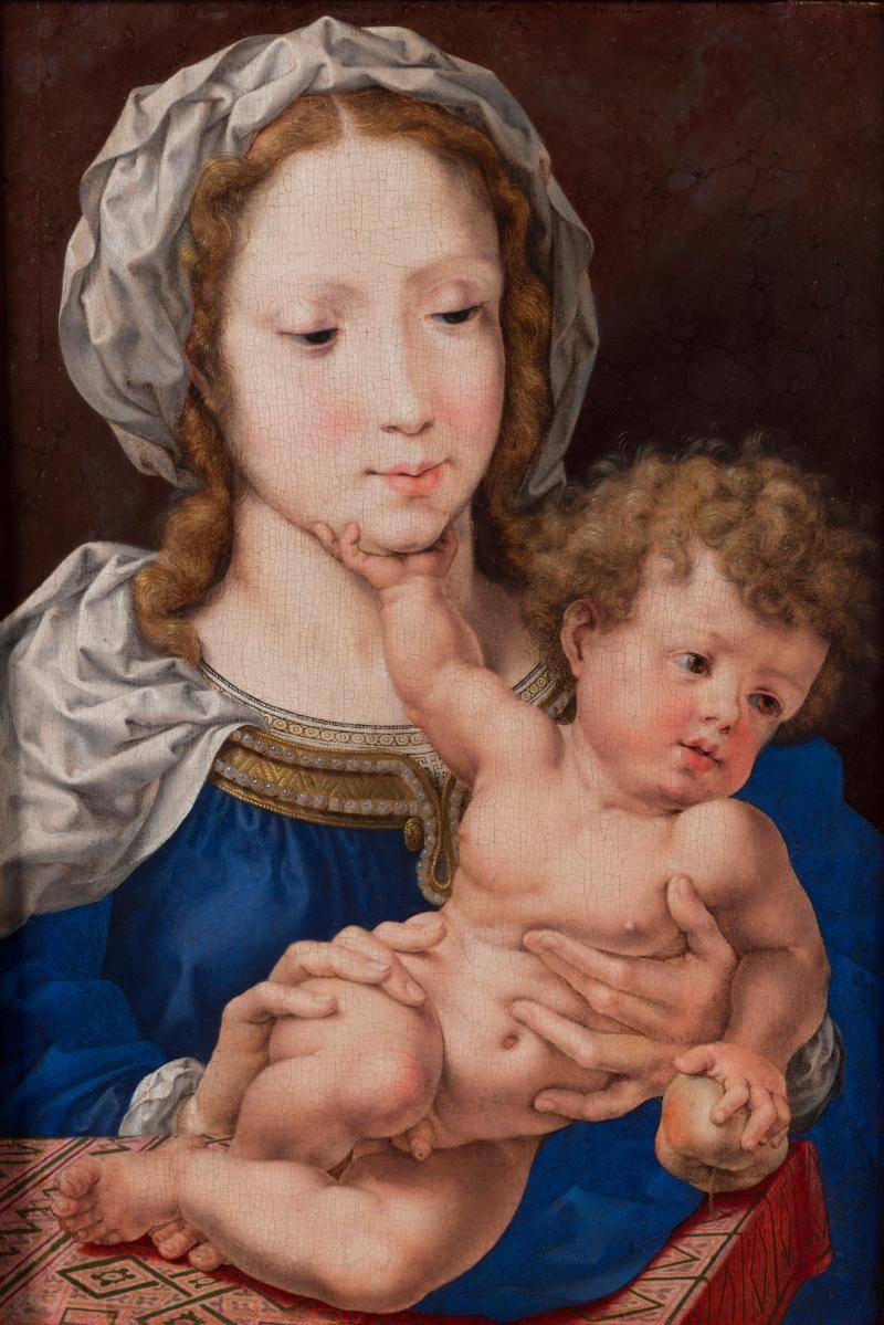 A mother in a blue dress and white cap holding her newborn baby