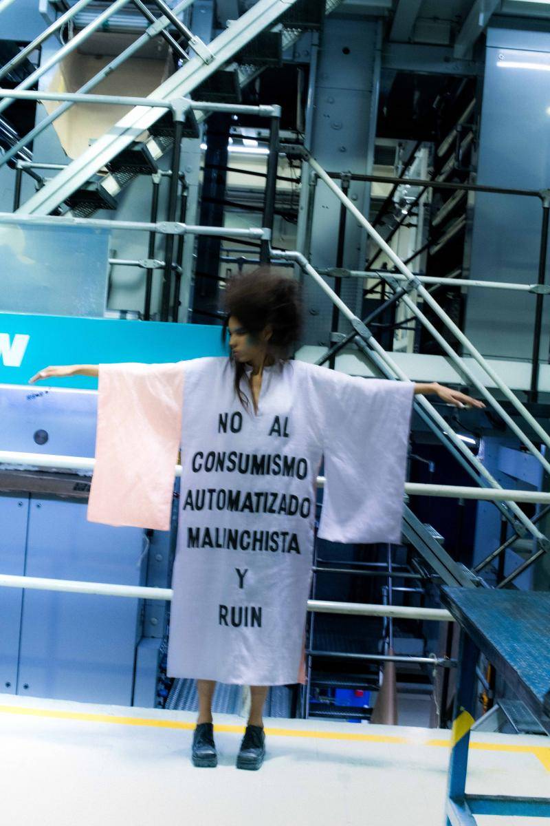 Model wearing a cloth with text in Spanish that reads, "No to malicious and mean automated consumerism"